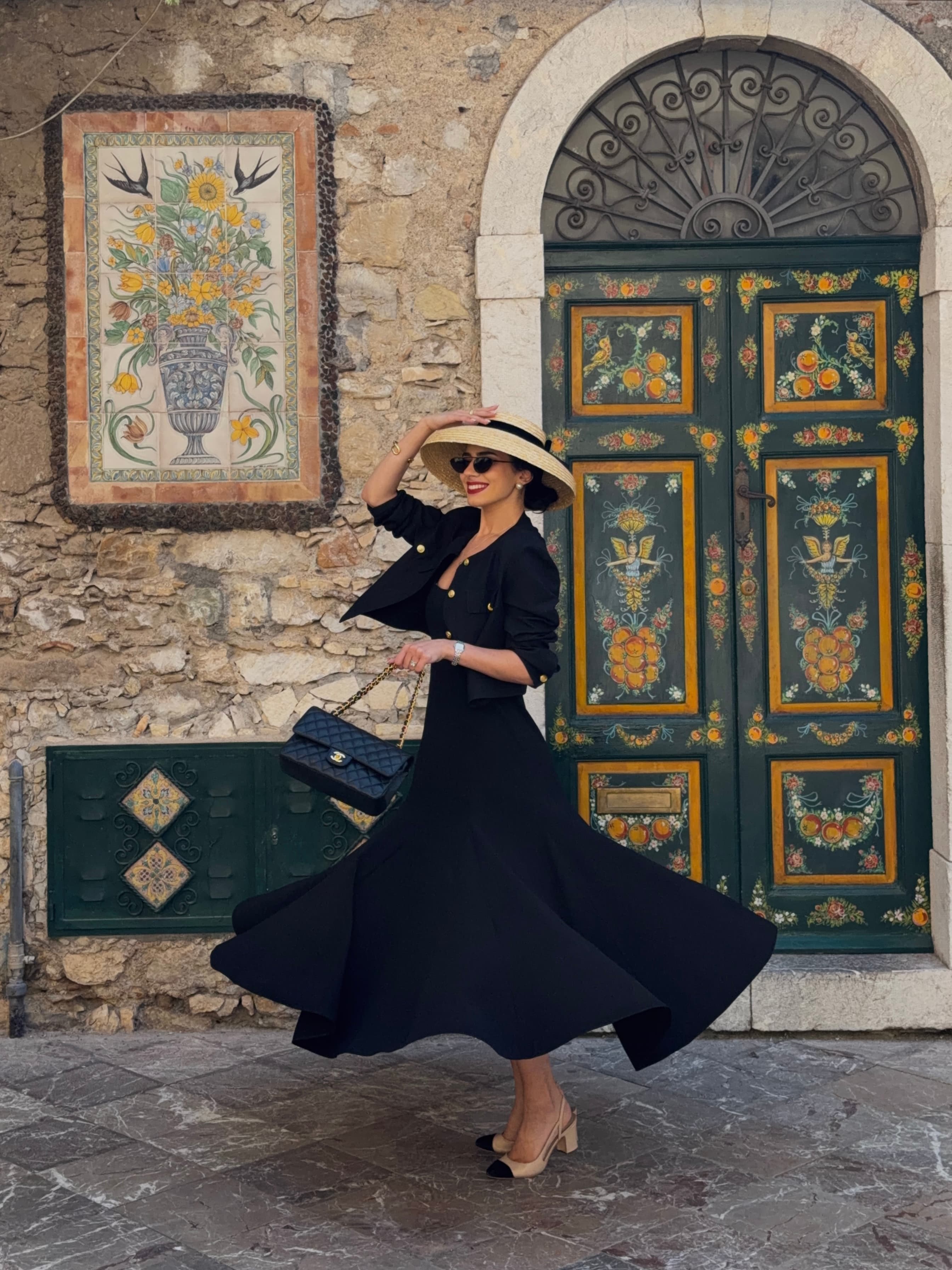 Chryssa Handis in a black dress and wide-brim hat while traveling